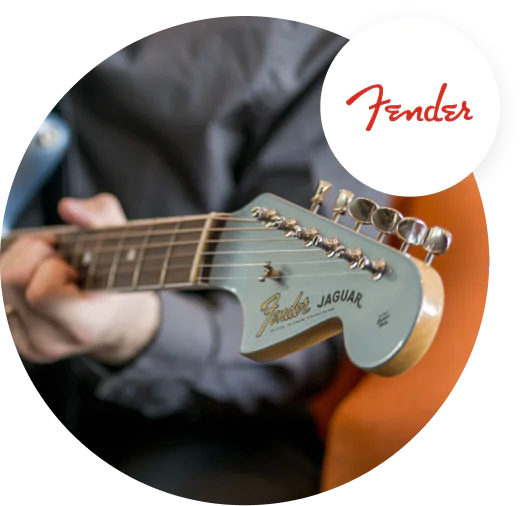 Close-up of a person playing a Fender Jaguar guitar with a focus on the guitar's headstock. Close-up of a person playing a Fender Jaguar guitar with a focus on the guitar's headstock.